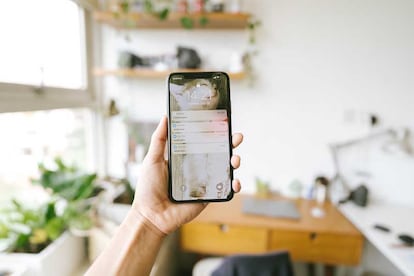 iPhone con la pantalla encendida en una mano