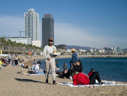 Un camarero lleva bebidas a las personas que disfrutan de las altas temperaturas en la playa de la Barceloneta, el pasado 25 de diciembre.