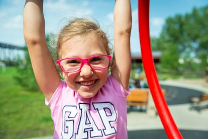 Una niña con gafas juega en un columpio.