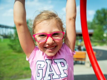 Una niña con gafas juega en un columpio.