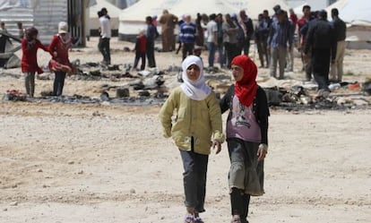 J&oacute;venes refugiadas sirias pasan ante restos quemados tras los incidentes registrados en el campo de Zaatari. 