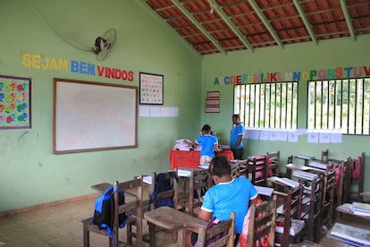 Uma das salas de aula, com carteiras de madeira, trabalhos dos alunos expostos na parede e uma aluna sentada, terminando de corrigir o texto ditado antes do recreio pela professora.