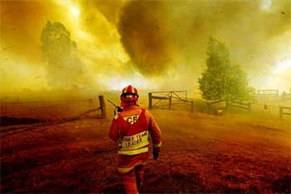 Un bombero observa impotente el avance del fuego en Victoria.