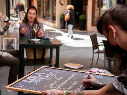 Una hostelera renueva la carta de su establecimiento en una terraza de un bar en Sevilla.