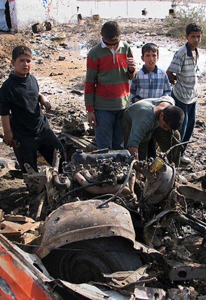 Niños iraquíes extraen piezas de un automóvil utilizado para perpetrar un atentado en las afueras de Bagdad.