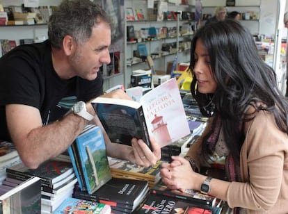 El escritor Mikel Alvira enseña la dedicatoria de su ultimo libro 'Llegará la lluvia' a una clienta.