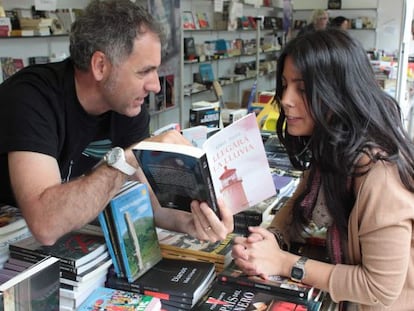 El escritor Mikel Alvira enseña la dedicatoria de su ultimo libro 'Llegará la lluvia' a una clienta.