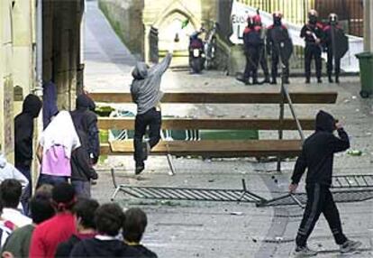 Un manifestante lanza una botella contra un grupo de <b></b><i>ertzainas</i> durante los incidentes del pasado domingo en San Sebastián.