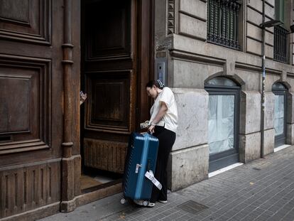 Dos turistas entran con sus maletas a un edificio donde hay un apartamento turístico en Barcelona.