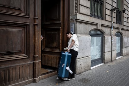Dos turistas entran con sus maletas a un edificio donde hay un apartamento turístico en Barcelona.