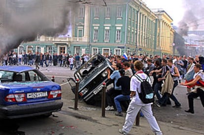 Un grupo de jóvenes se dedica a volcar coches, el domingo, en una calle moscovita.