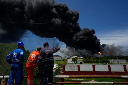 Según un responsable de la empresa estatal petrolera, CUPET,  este es el mayor incendio registrado en la isla. En la imagen, trabajadores de la CUPET observan la columna de humo generada por el incendio, la tarde del 6 de agosto de 2022.