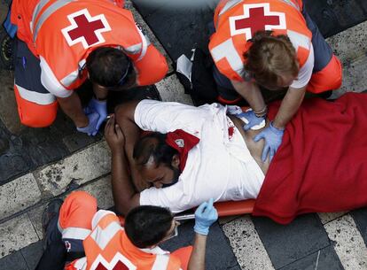 Personal sanitario atiende a uno de los heridos por asta de toro durante el segundo encierro de los Sanfermines.