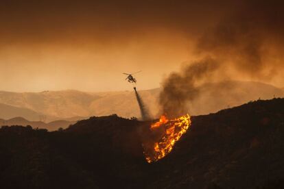 El bautizado como Fuego de Arena comenzó en la tarde del viernes y se ha extendido rápidamente en una zona situada a unos 65 kilómetros al noroeste de la ciudad. En la imagen, un helicóptero lanza agua a las llamas cerca de Santa Clarita, California.