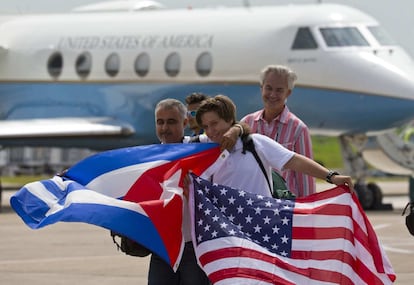 Pasajeros del vuelo 387 de jetBlue sujetan una bandera estadounidense y una cubana frente a un avión de transporte estadounidense, en el Aeropuerto Internacional Abel Santamaría (Cuba). 