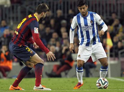 El delantero mexicano de la Real Sociedad, Carlos Vela (d), controla el balón ante el defensa del F. C. Barcelona, Gerard Piqué, durante el encuentro correspondiente a la ida de la semifinal de la Copa del Rey, que disputan esta noche en el estadio del Camp Nou. 