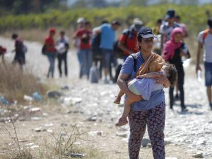 Un grupo de refugiados cruzan la frontera entre Grecia y Macedonia.-