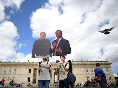 Dos hombres posan con los carteles de ambos candidatos en Bogotá.