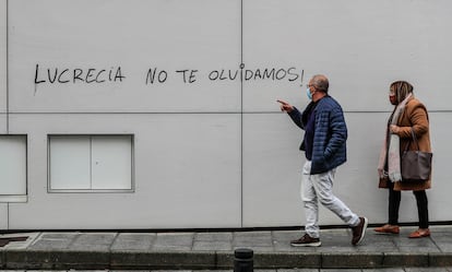 Dos personas pasan delante de una pintada en la plaza de la Corona Boreal, en Aravaca (Madrid).