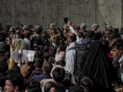 Um homem segura seu passaporte diante dos militares que guardam o aeroporto de Cabul. 
