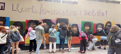 Vecinos del barrio de la Ribera de Barcelona limpiando el mural feminista vandalizado. Agachada con chaqueta roja, Mariel Soria, autora del mural.