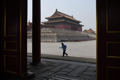 Un empleado de limpieza con mascarilla camina por la Ciudad Prohibida, este viernes 1 de mayo