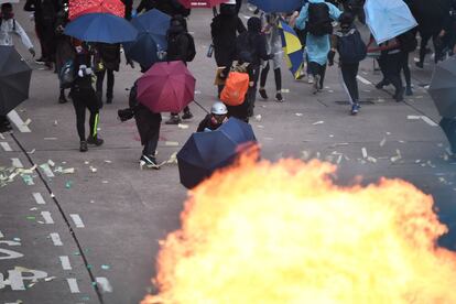 Personas y manifestantes se protegen con paraguas, mientras se producen violentas protestas en las calles de Hong Kong en protesta por la presencia china.