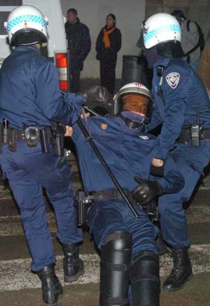 Un agente de la Guardia Urbana es trasladado por sus compañeros tras ser herido este sábado, durante los enfrentamientos en la Rambla del Raval (Barcelona).