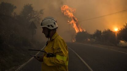 Un bombero pasa por una carretera durante un incendio en Granada.