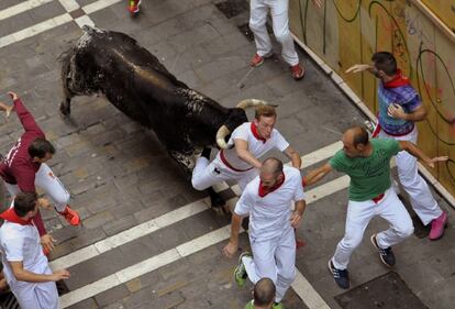 Uno de los toros de la ganadería madrileña de Victoriano del Río golpea a un mozo en la calle de La Estafeta durante el sexto encierro de los Sanfermines.