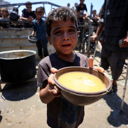 A Palestinian child holds a bowl with food received from a charity kitchen, amid a hunger crisis, in Gaza City, July 24, 2025. REUTERS/Dawoud Abu Alkas     TPX IMAGES OF THE DAY