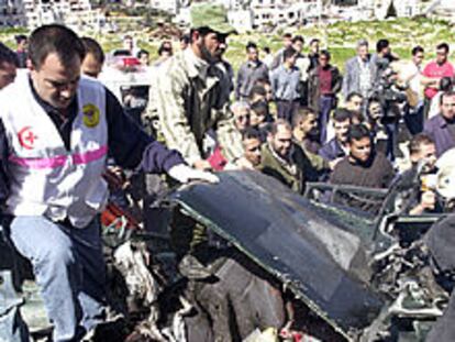 Sanitarios palestinos revisan un coche destruido por un misil israelí en Ramala.