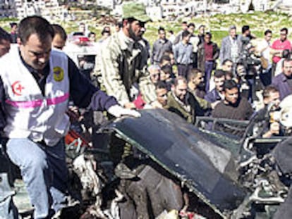 Sanitarios palestinos revisan un coche destruido por un misil israelí en Ramala.