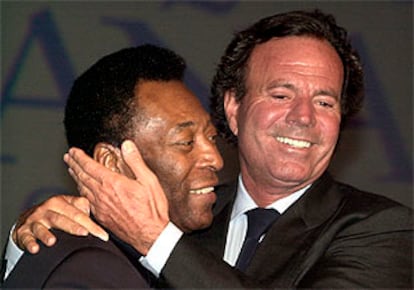 El cantante Julio Iglesias saluda afectuosamente al <b></b><i>cantante</i> Pelé, ambos embajadores de Unicef, durante el acto celebrado ayer en Sevilla con motivo de la reunión anual del Fondo Mastercard de Ayuda a la Infancia.