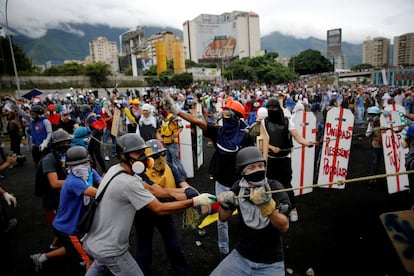 Varios manifestantes emplean cuerdas para echar abajo una cerca en el perímetro de una base de la fuerza aérea venezolana, el 24 de junio de 2017.