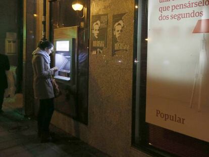Una clienta utilitza el caixer d'una oficina del Popular a Madrid.