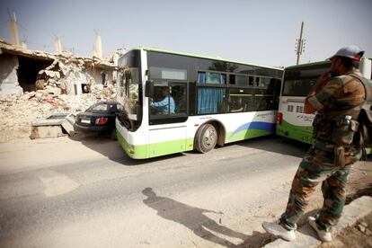 Un soldado del Ejército sirio observa cómo los civiles montan en autobuses para ser evacuados de Daraya.