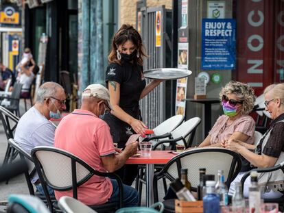 Una camarera sirve una mesa en una terraza de Benidorm.