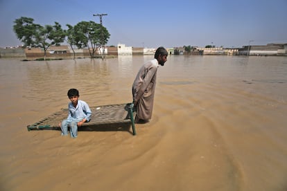 Un hombre transporta a su hijo por una zona inundada tras las fuertes lluvias en el distrito de Nowshera, este martes. El Gobierno de España enviará 300.000 euros a Pakistán para atender la crisis humanitaria provocada por las inundaciones de los últimos días.