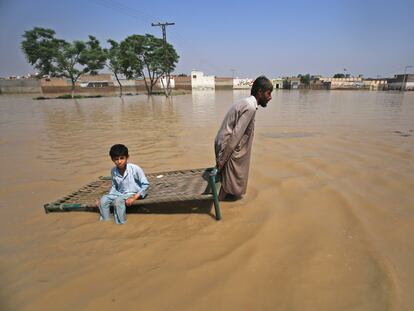 Un hombre transporta a su hijo por una zona inundada en Pakistán, en septiembre de 2022.