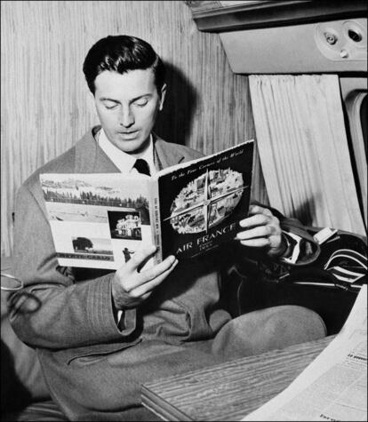 Givenchy lee una revista durante un vuelo, en 1957.