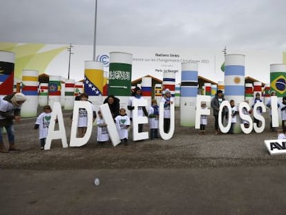 Niños muestran el mensaje "adieu Fossil Fuels" (adiós a los hidrocarburos) durante la Conferencia sobre el Cambio Climático de París (Francia).