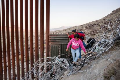 A woman and a girl cross the wall in a desert area near Jacumba, California.