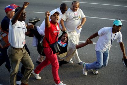 Personal de seguridad retira a un hombre durante la marcha por el Día del Trabajo en La Habana (Cuba).