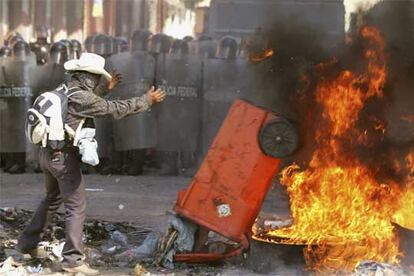 Un manifestante empuja un contenedor de basura a una barricada en llamas ayer en Oaxaca.