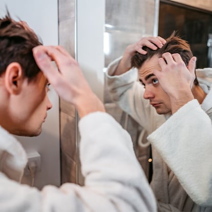 Una chico mirando si tiene entradas en el pelo.