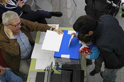Un niño introduce el voto de su padre en la urna en Barcelona.