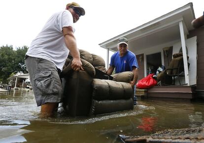 Dos hombres retiran del interior de su casa mobiliario dañado, en Sorrento, Luisiana (EE.UU).