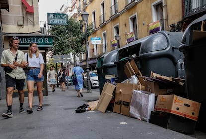 Una pareja mira los residuos que hay fuera de los contenedores en la calle de la Magdalena de Madrid, este lunes.