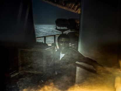 <p>'La travesía' es un proyecto fotográfico de Andrew McConnell de Panos Pictures basado en retratos nocturnos y testimonios de personas rescatadas en el Mediterráneo por el barco Prudence de Médicos Sin Fronteras durante julio de 2017.</p> <p> "El proyecto consiste en una serie de retratos nocturnos realizados a bordo del Prudence", explica Andrew McConnell. Las imágenes fueron tomadas desde tres ubicaciones: la zona de búsqueda y rescate frente a la costa de Libia, en medio del mar Mediterráneo y en la costa de Sicilia. Las fotografías son de tono sombrío, elemento importante que habla de la experiencia de cualquiera que haya intentado cruzar el Mediterráneo. Cada retrato está acompañado de un testimonio que explica las razones por las que las personas han abandonado su hogar y arriesgado sus vidas en este viaje.</p> <p>"El personaje principal de la serie es el mar Mediterráneo. Este se ve en cada toma, sus reflejos iluminados por la luna giran y bailan dentro del marco, a menudo fusionándose con la persona. Está siempre presente, como un centinela caprichoso, decidiendo quién pasará y quién no. En muchas de las imágenes, el individuo parece estar sumergido en el mar, de hecho no está claro si se hunden o no o si están saliendo del agua. El efecto se suma al misterio de la serie y el espectador debe preguntarse: ¿Estamos viendo fotos de fantasmas? Así, las imágenes son en última instancia un reconocimiento de las vidas que se han perdido en el Mediterráneo en los últimos años".</p>